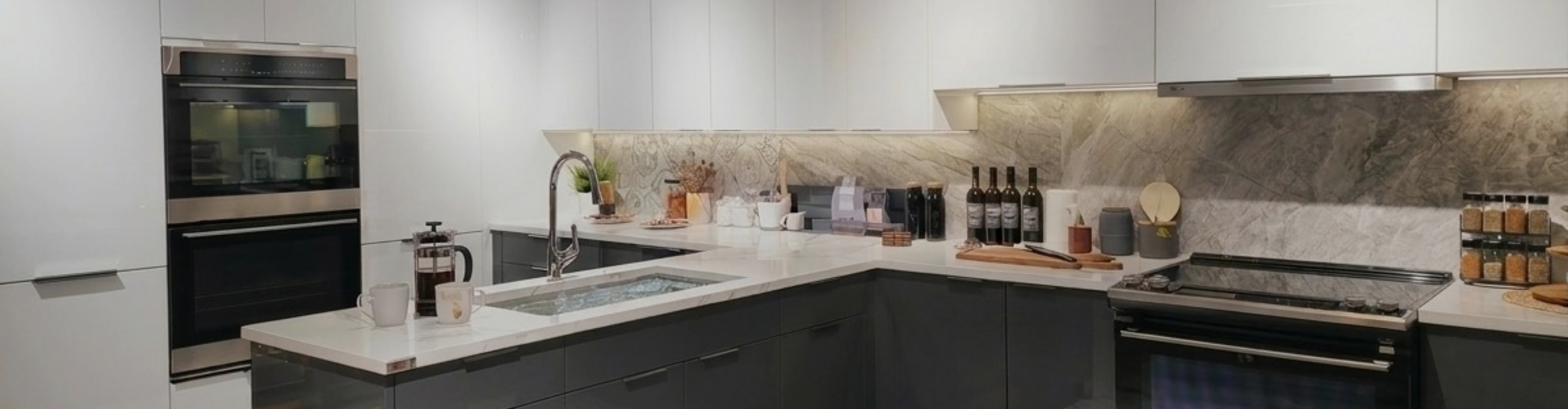 White luxury cabinets with silver hardware in a kitchen with marble countertops and backsplash.